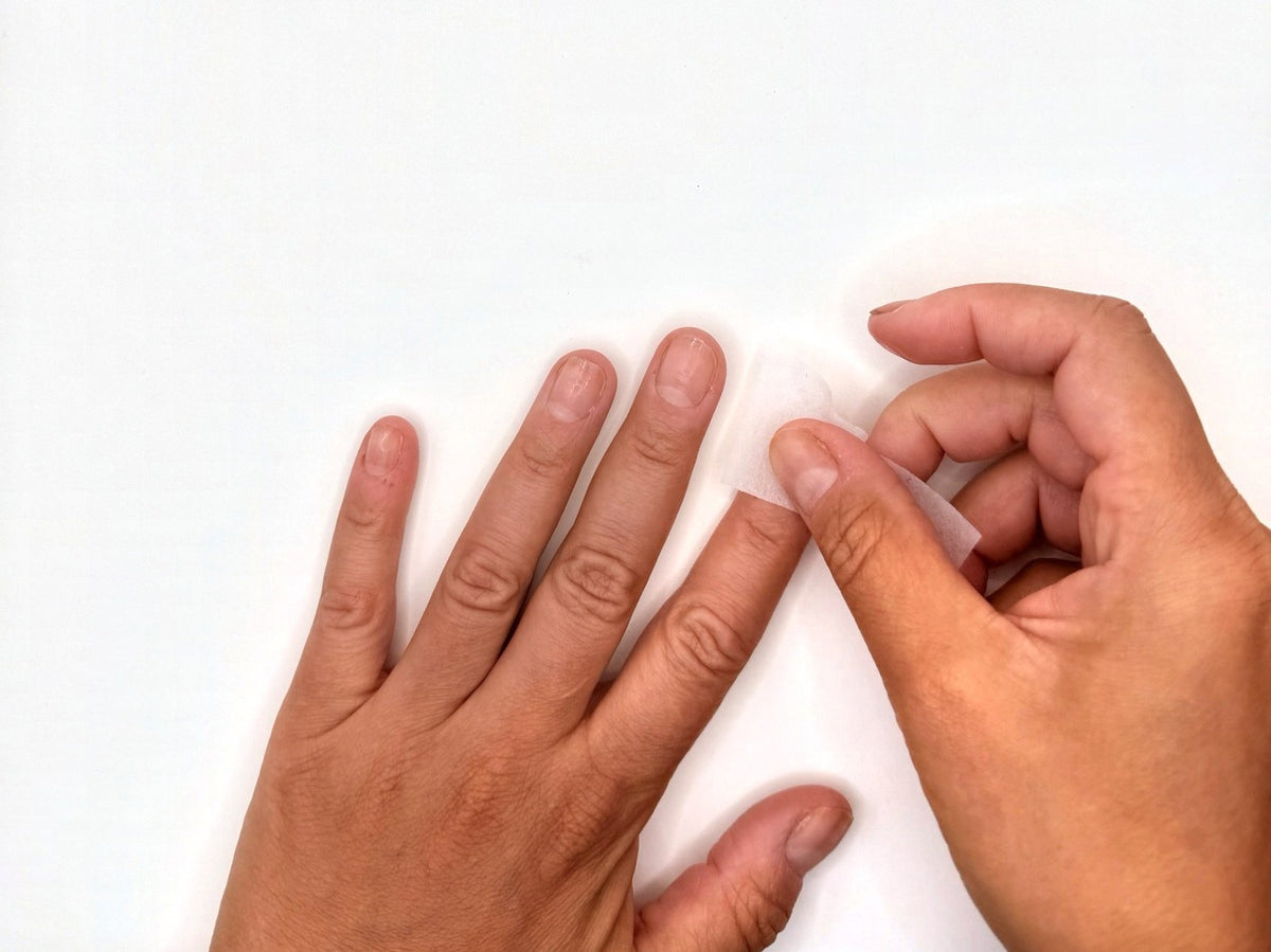 Wiping natural nails with an alcohol pad to remove oils before application