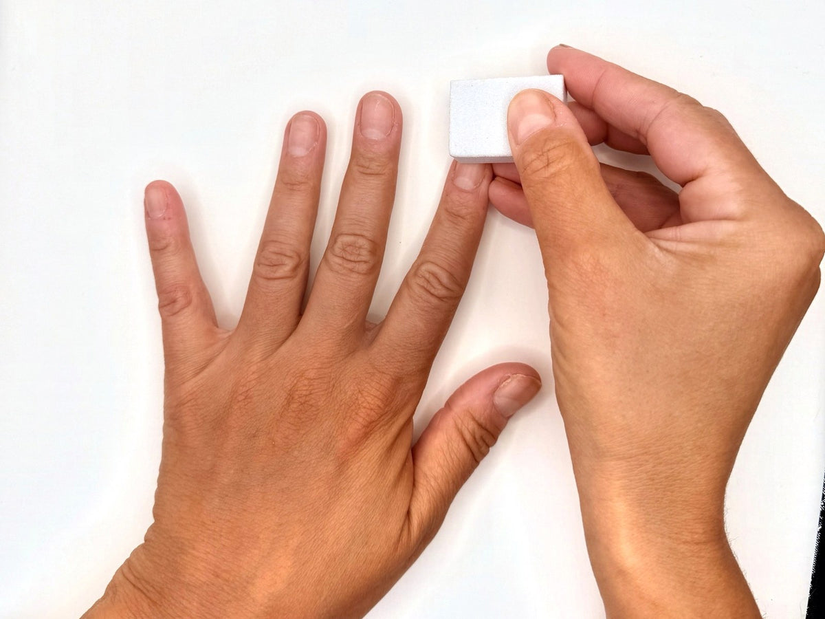 Lightly buffing a natural nail with a buffing block to remove shine