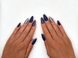 Both hands side by side with a full set of navy matte and glitter press-on nails